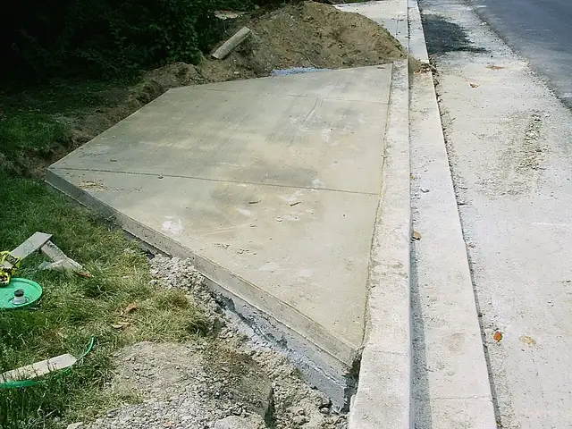 Concrete driveway apron meeting a sloped street curb
